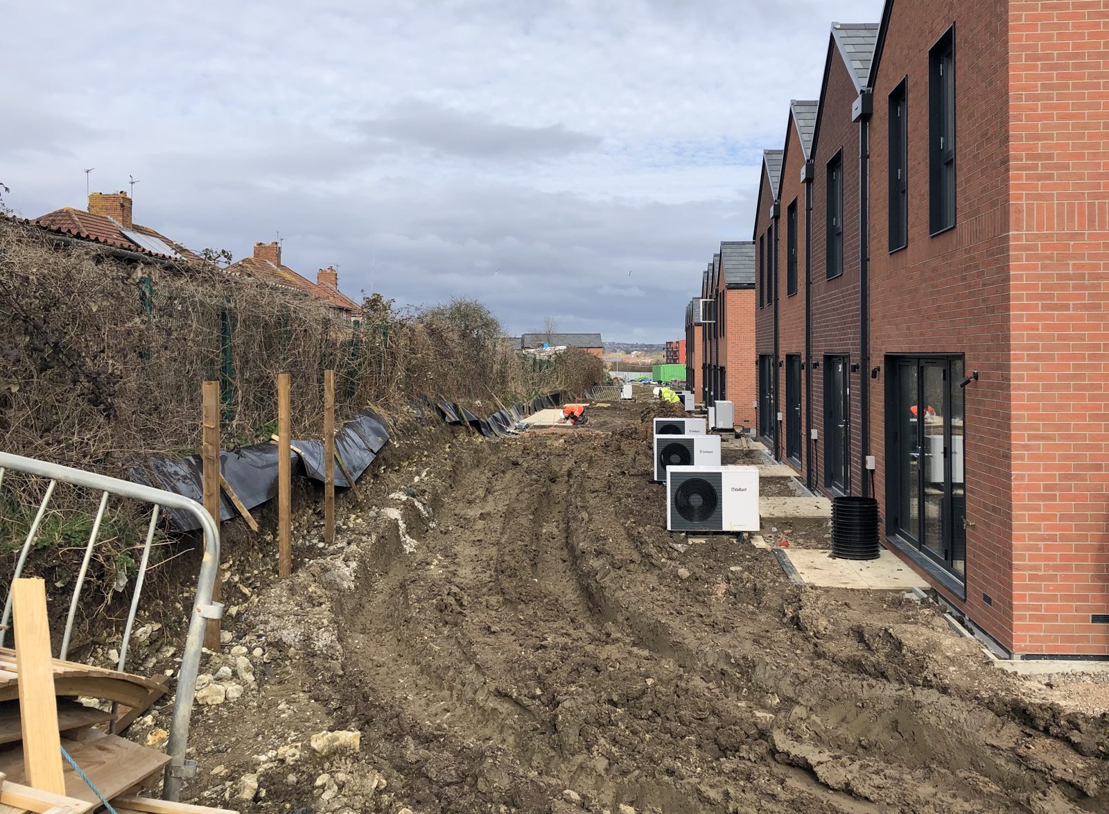 Row of exposed heat pumps along new homes during groundworks