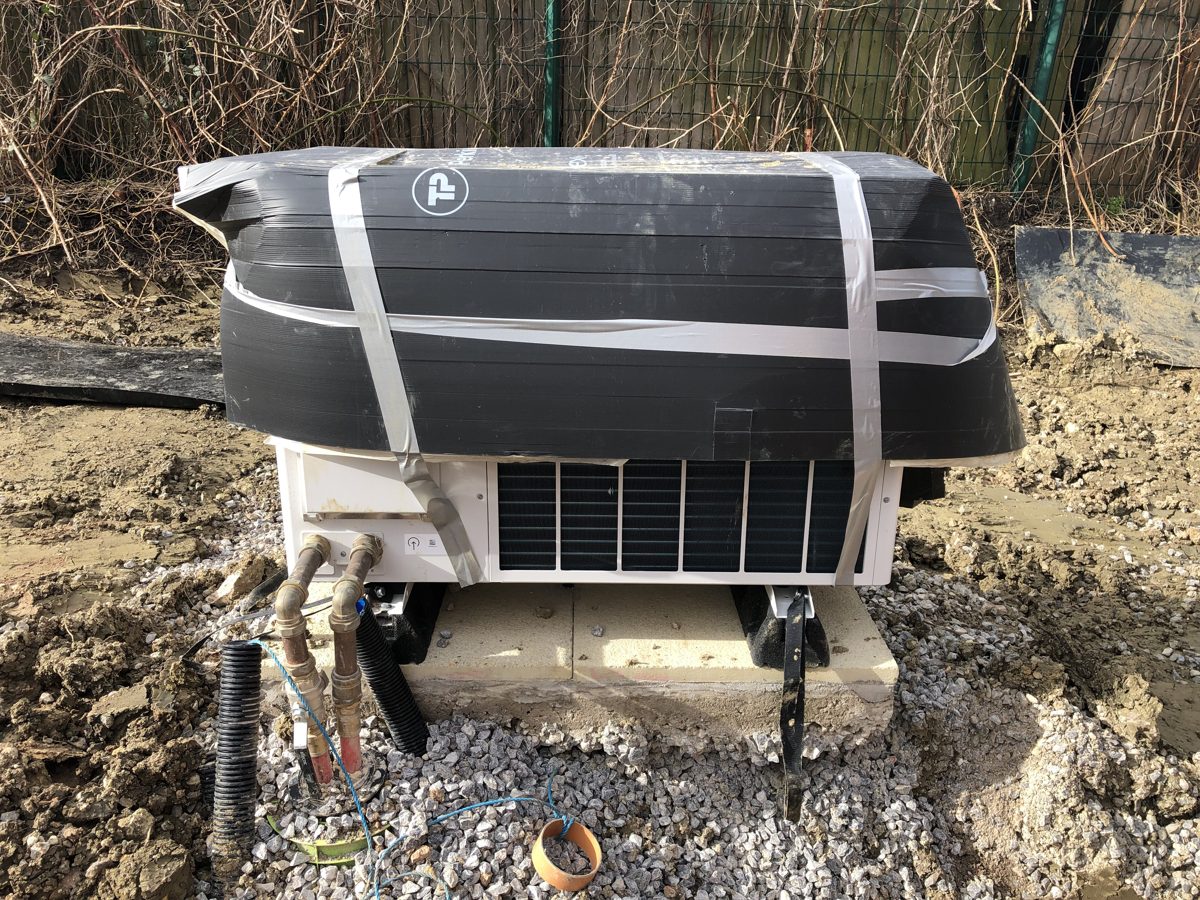 Heat pump with plastic strapped over the top only, pipework exposed
